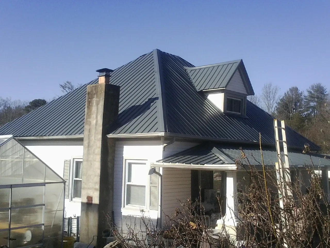 Dark blue standing seam metal roof on a white farmhouse with dormer — Slate & Tile Roof Repair by Roofing Brothers in Reading