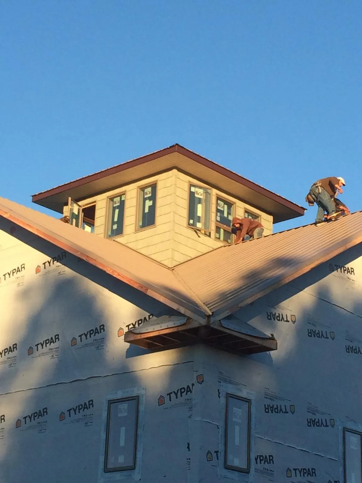 Roofers working around a rooftop cupola on a new metal roof at sunset — Roof Waterproofing in Reading by Roofing Brothers